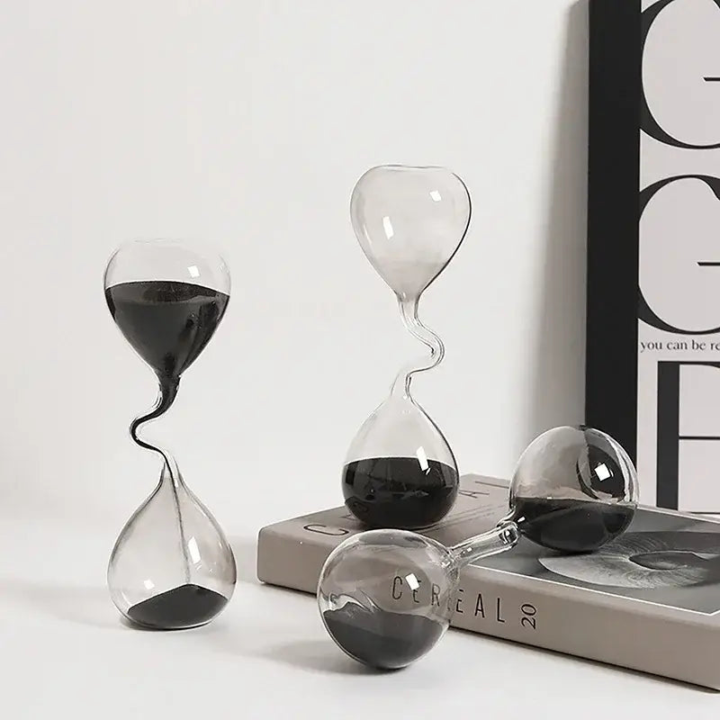 three elegant glass hourglass timers with black sand featuring unique twisted and heart-shaped designs for sand timer home decoration