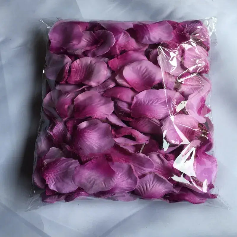 A bag of 5500 colorful artificial pink rose petals with a gradient from deep magenta to lighter shades made of satin-like fabric for wedding decor.