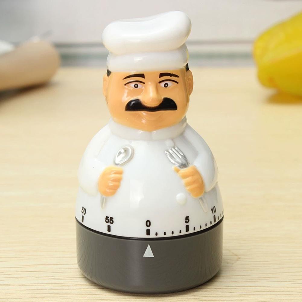Mechanischer Küchenkoch-Timer mit einer weißen Kunststoff-Kochfigur mit schwarzem Schnurrbart, die silberne Utensilien hält, sowie einem grauen Sockel mit nummerierten Markierungen für bis zu 60 Minuten.