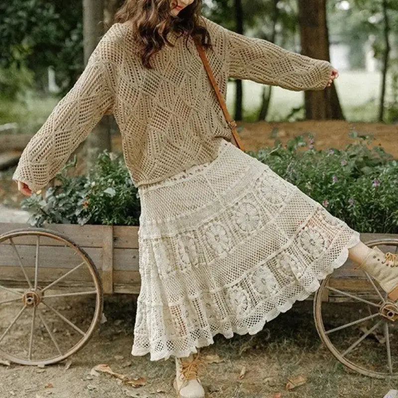 Beige crochet sweater with intricate diamond-patterned knit and long sleeves paired with an off-white crochet lace maxi skirt for summer wear.