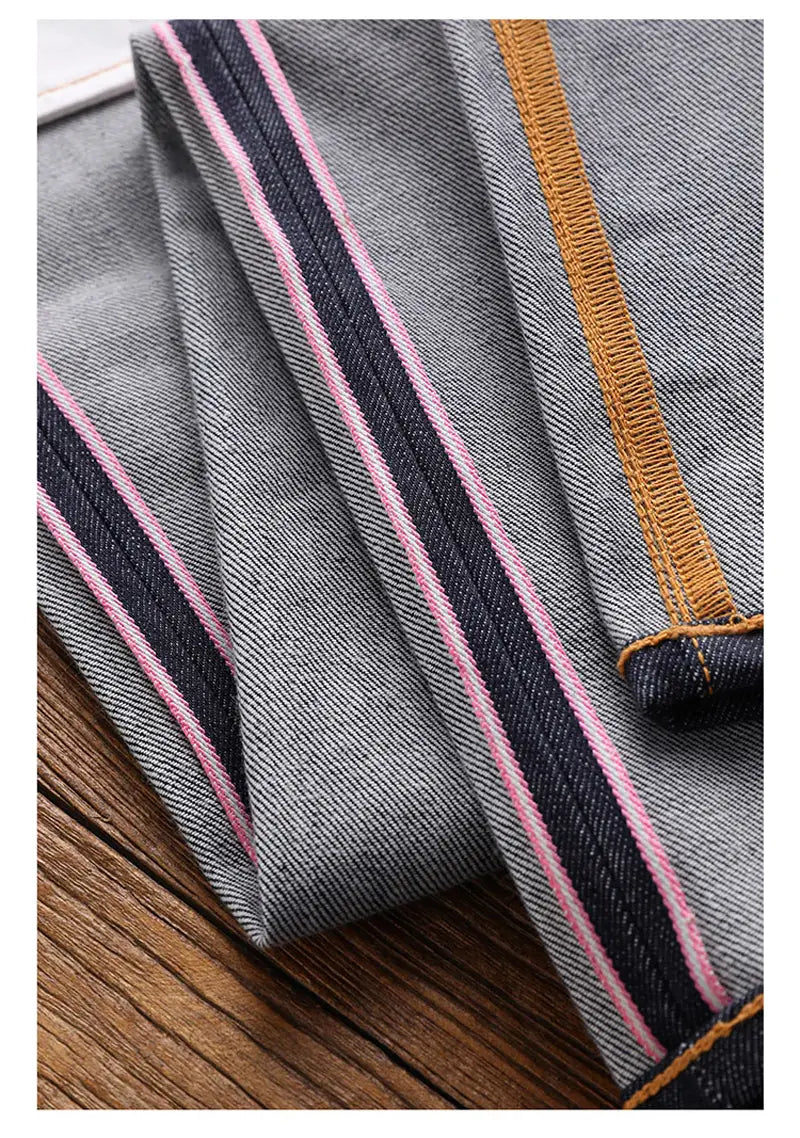 Jeans en denim gris « red tornado » en selvedge slim droit 16 oz, avec des détails à rayures rose et noires le long des coutures et des surpiqûres beige.