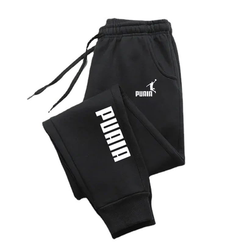 Joggers impresos de hombre estilo casual streetwear, sudaderas tipo pantalón en color negro, con logotipo y letras de Puma en color blanco en la pierna.