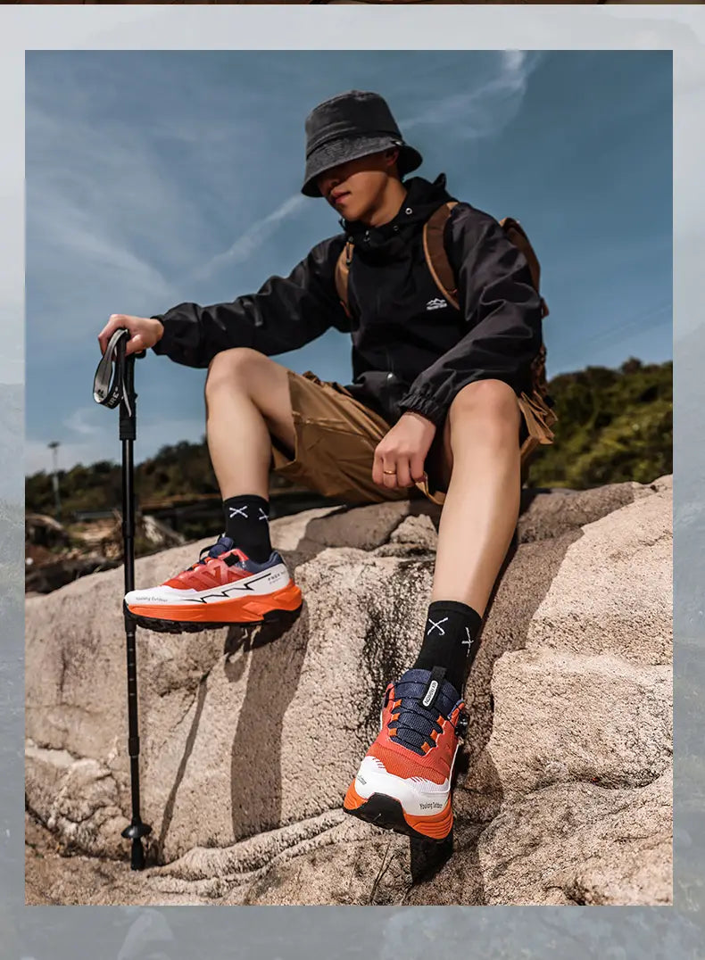 Men hiking shoes waterproof lightweight trekking sneakers in orange and white with navy blue accents shown from the back side.
