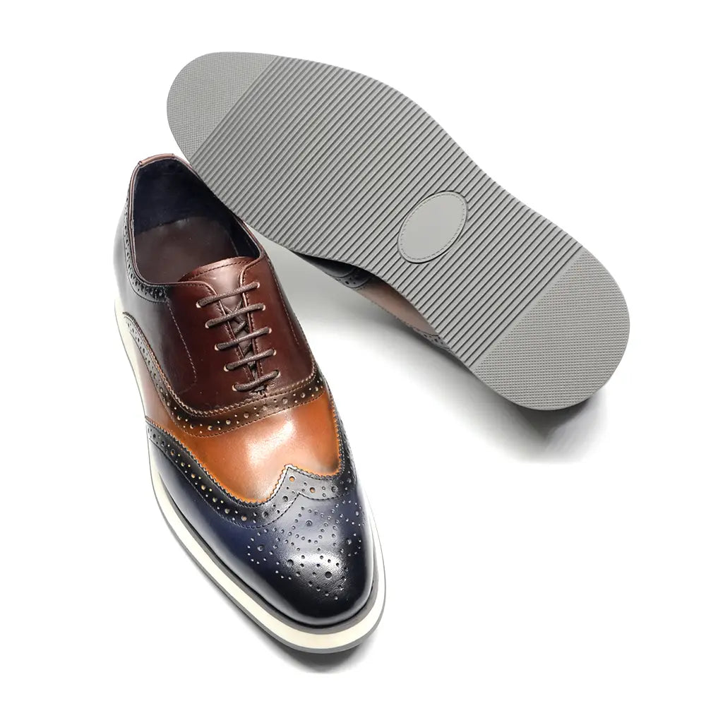 Escarpins brogue wingtip en cuir marron et bleu marine bicolore, avec des accents en cuir camel, mettant en valeur un motif brogue classique.