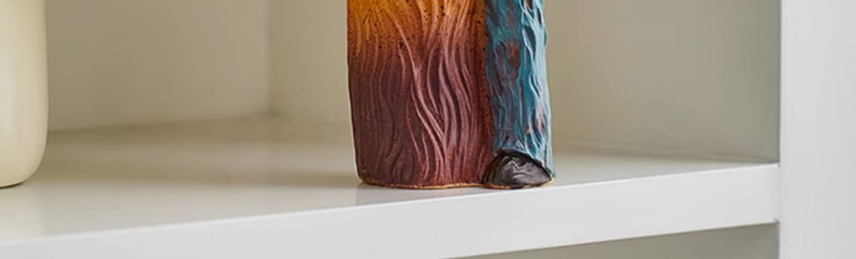 A ceramic resin family figurine abstract art home decor vase with a textured wavy surface and an orange to brown gradient finish.