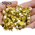 A hand holds fifty shiny gold-colored metal mini bell pendants for Christmas decorations and DIY handicrafts