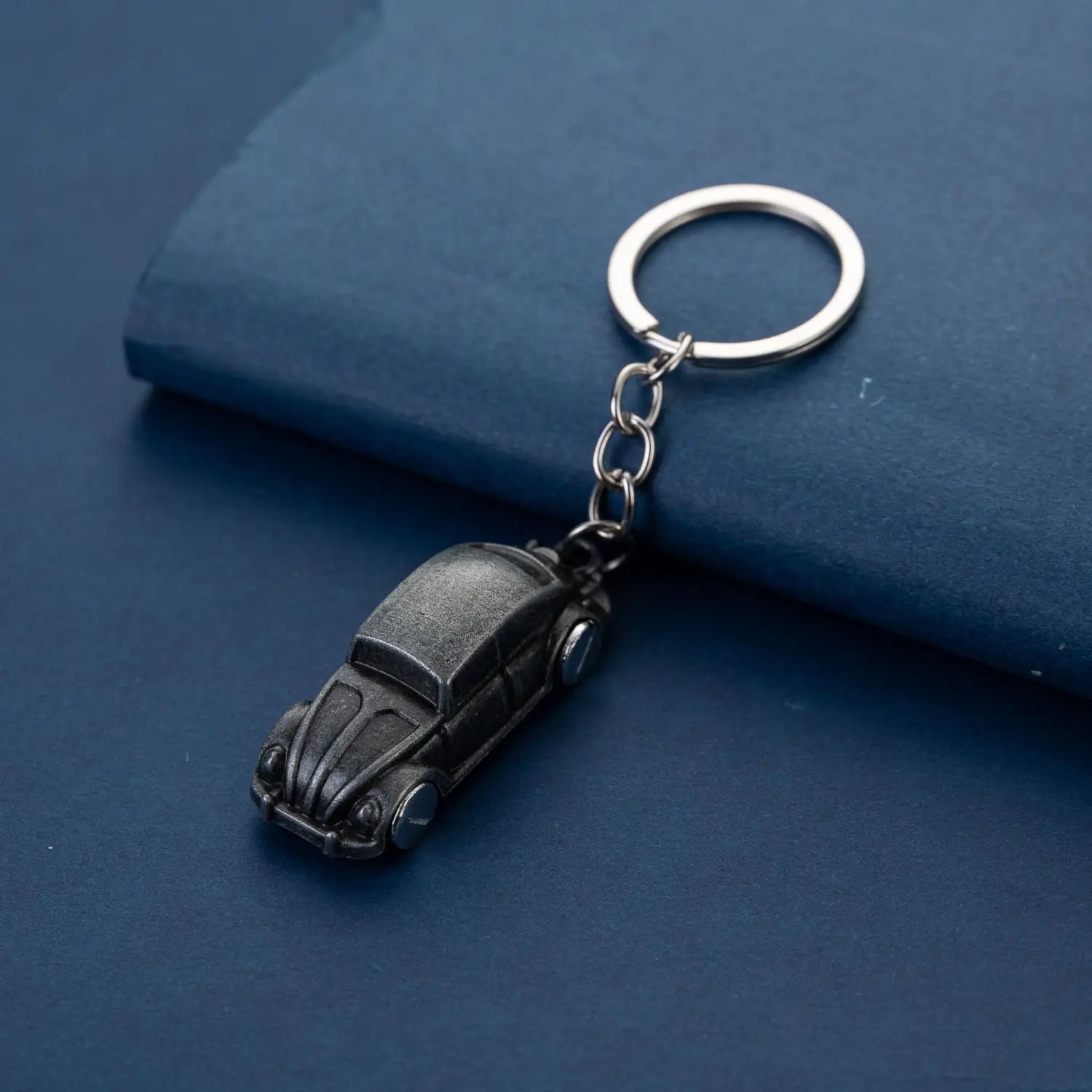 Black vintage-style Volkswagen Beetle metal car keychain with a silver ring and chain for keys.