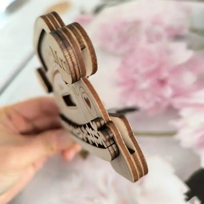 Eine hellbraune hölzerne Geschenkbox für Geld zum Aufbewahren in Form eines Hochzeitswagens mit einem Puzzleteil in Form eines lächelnden Gesichts, mit aufwendigen Ausspar-Details und geschichteten Kanten