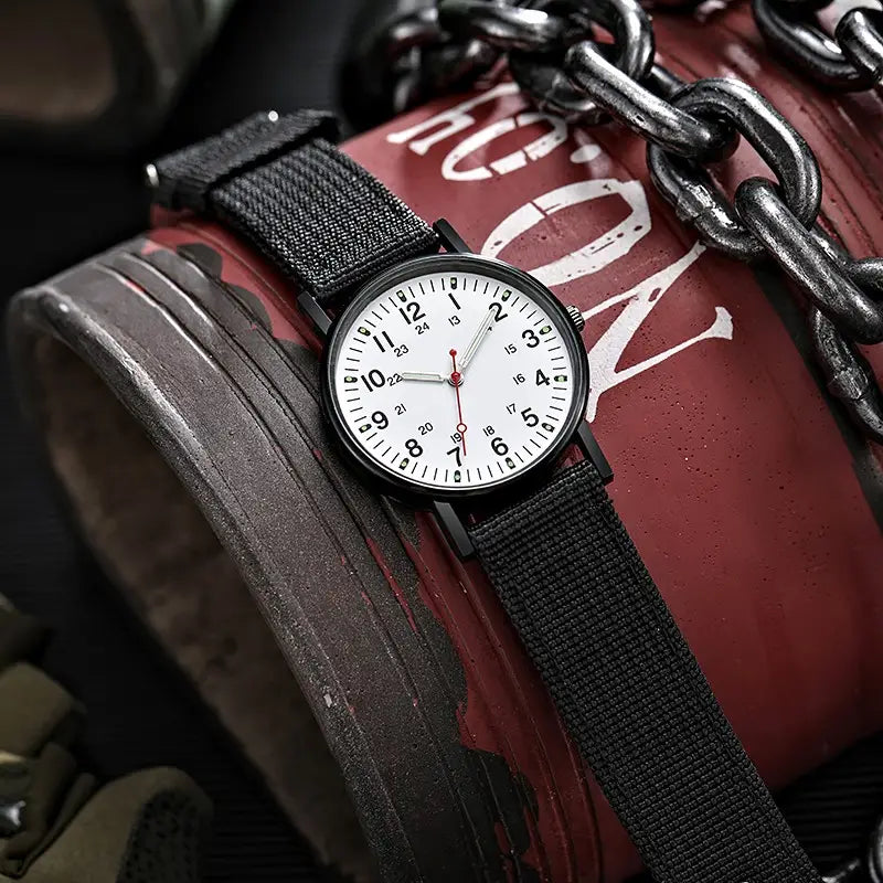 Militärisches Quarzarmbanduhr mit schwarzem Nylonarmband, weißem Zifferblatt mit schwarzen Stundenmarkierungen und Zeigern sowie rotem Sekundenzeiger in minimalistischer Gestaltung.