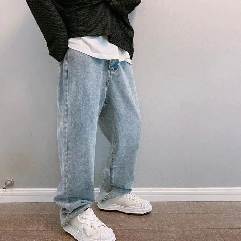 Pantalon cargo en jean à jambes larges à effet délavé clair avec broderie croisée noire, coupe décontractée et délavage subtil.