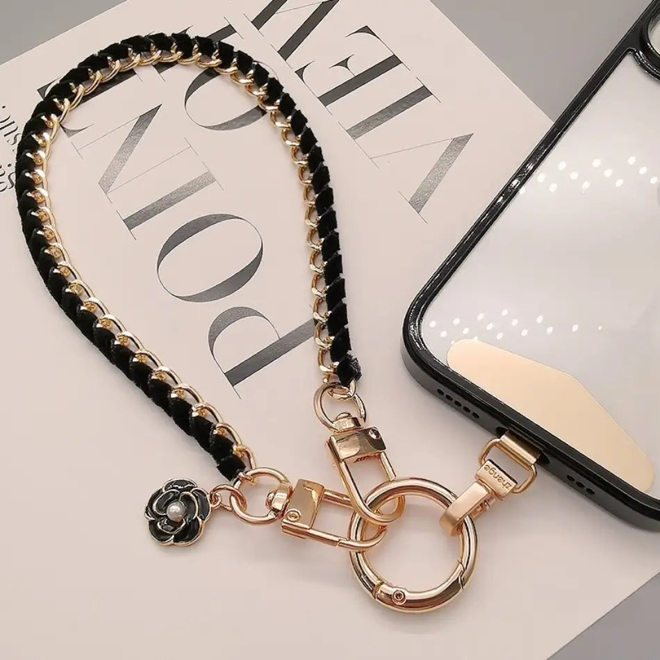 Schwarzer und goldfarbener Ketten-Handy-Handgelenkriemen mit floralen Anhänger zur Verwendung als Anti-Lost-Handylanyard.