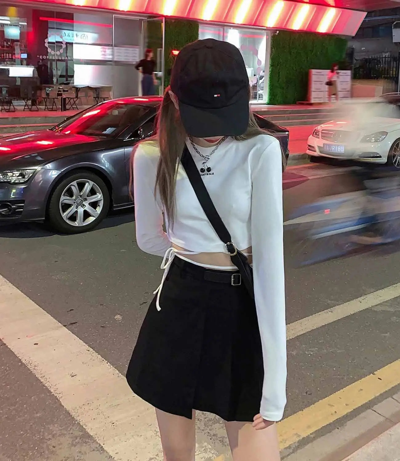 Damen-Langarm-Crisscross-Crop-Top, abgebildet mit einer schwarzen Baseballkappe mit kleinem weißem Logo vorne