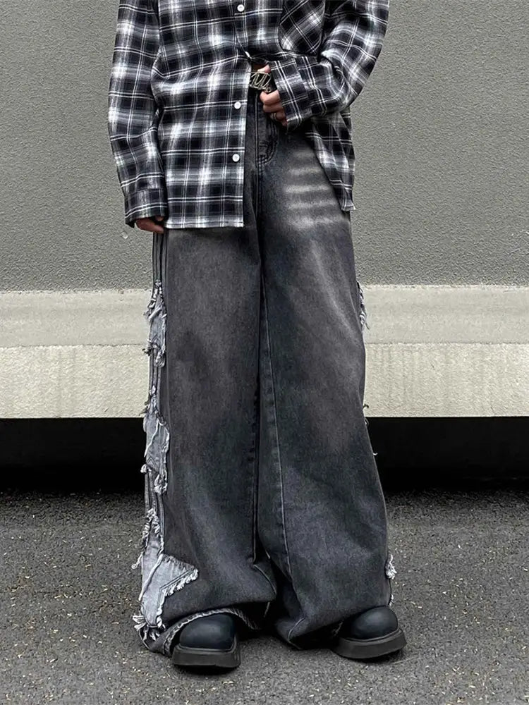 Jeans denim wide-leg gris foncé fabriqué dans un denim délavé et déchiré, avec des finitions effilochées le long des côtés, provenant de la collection de jeans en denim délavé et déchiré baggy style Y2k.