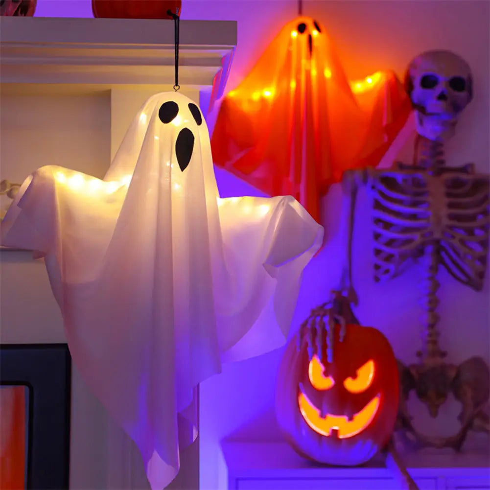 A glowing white LED hanging ghost Halloween decoration made of translucent fabric with black eye and mouth cutouts.