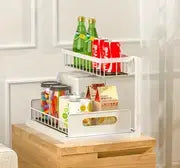 Organisateur d’évier en forme de L à deux niveaux en plastique blanc, avec compartiments transparents pour contenir des aliments en conserve et des boissons en bouteille, pour une utilisation dans les placards de cuisine et de salle de bains