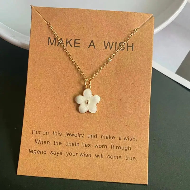Un collier délicat en chaîne à maillons en or, présentant un petit pendentif de fleur blanche avec une micro-pierre au centre, dans un style romantique et mignon.