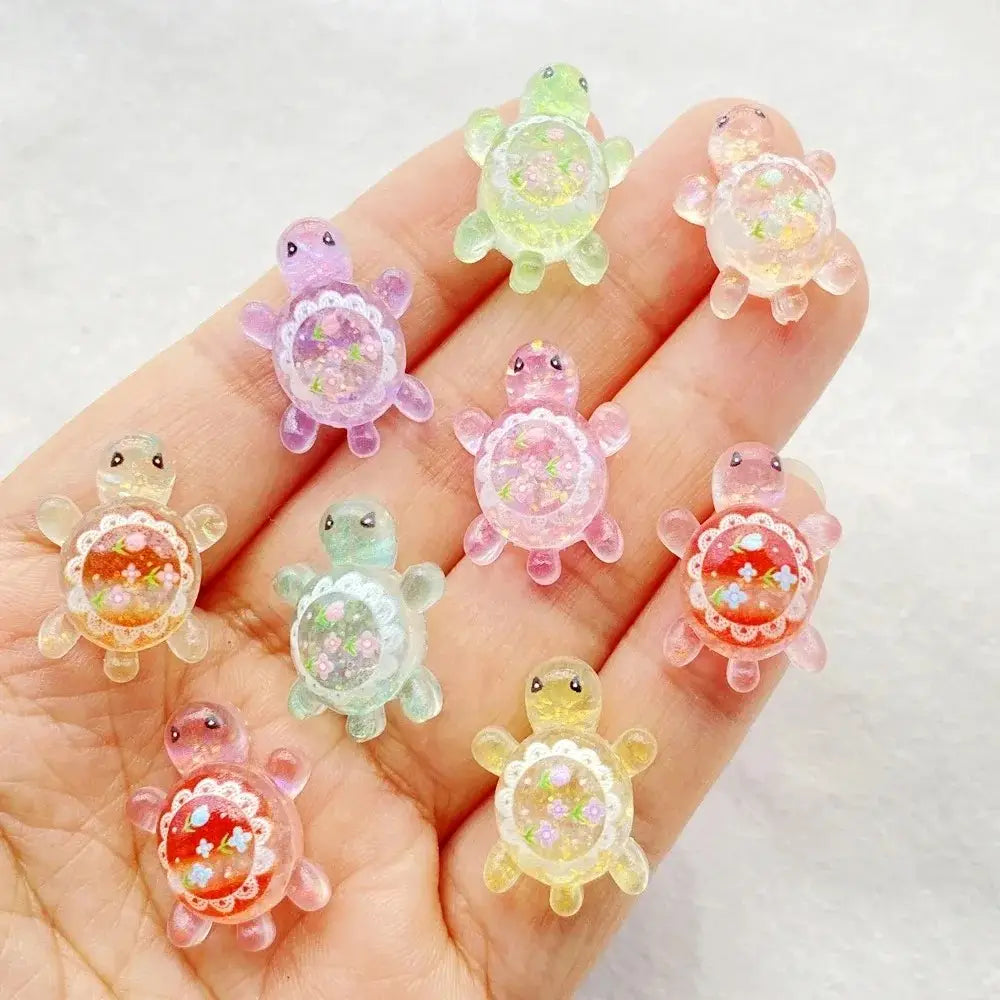 resin turtle flatback charms 10 pack featuring pastel-colored resin with floral glitter interiors and delicate lace-like detailing around the shell.