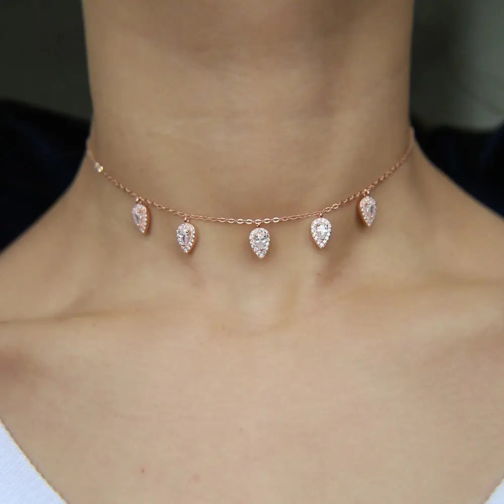 Collar tipo gargantilla delicado en color dorado rosa, adornado con cinco cristales cz en forma de gota de lágrima.
