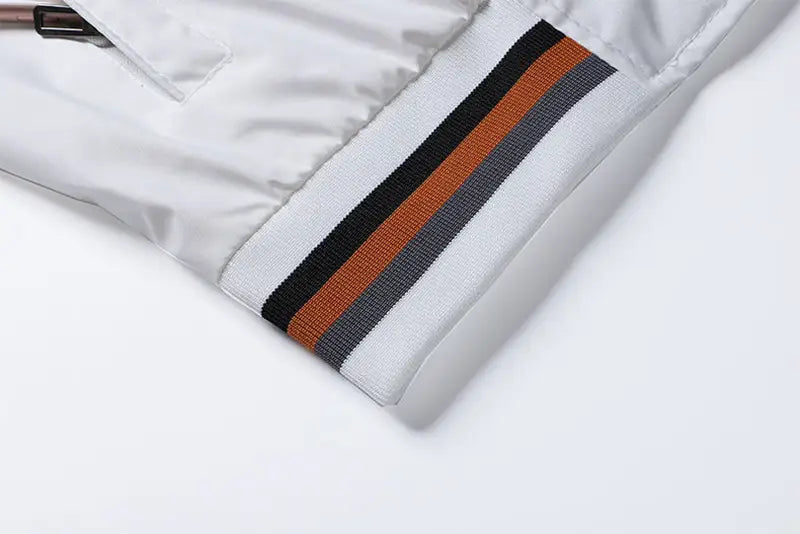 Puño de la manga de la chaqueta tipo bomber USA para hombre, con gráfico de letras estilo varsity, abrigo casual, en satén blanco con canalé a rayas negro, naranja y gris.