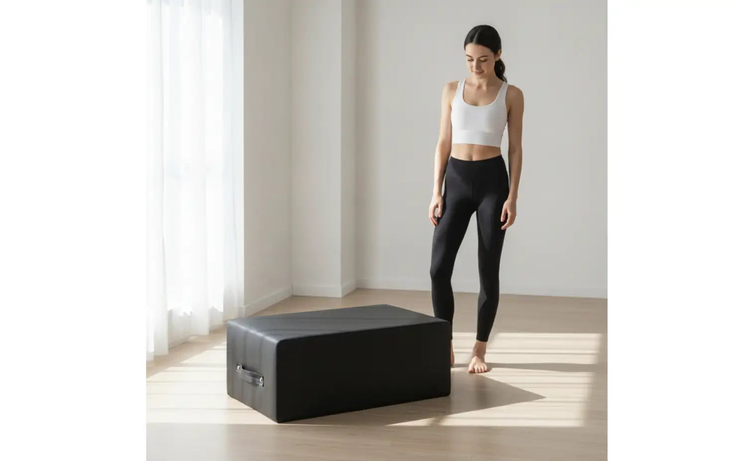 Schwarze rechteckige, gepolsterte Fitnessbox für Pilates und das Home-Gym mit einem metallischen Griff an der Seite sowie einer Pilates-Reformer-Mattenoberfläche