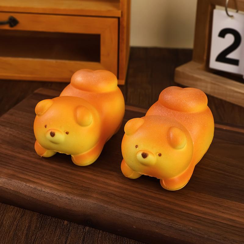Two orange and yellow slow rising toast fidget toys shaped like squishy dogs with soft plush textures designed for stress relief and daily stress management as desktop decoration.