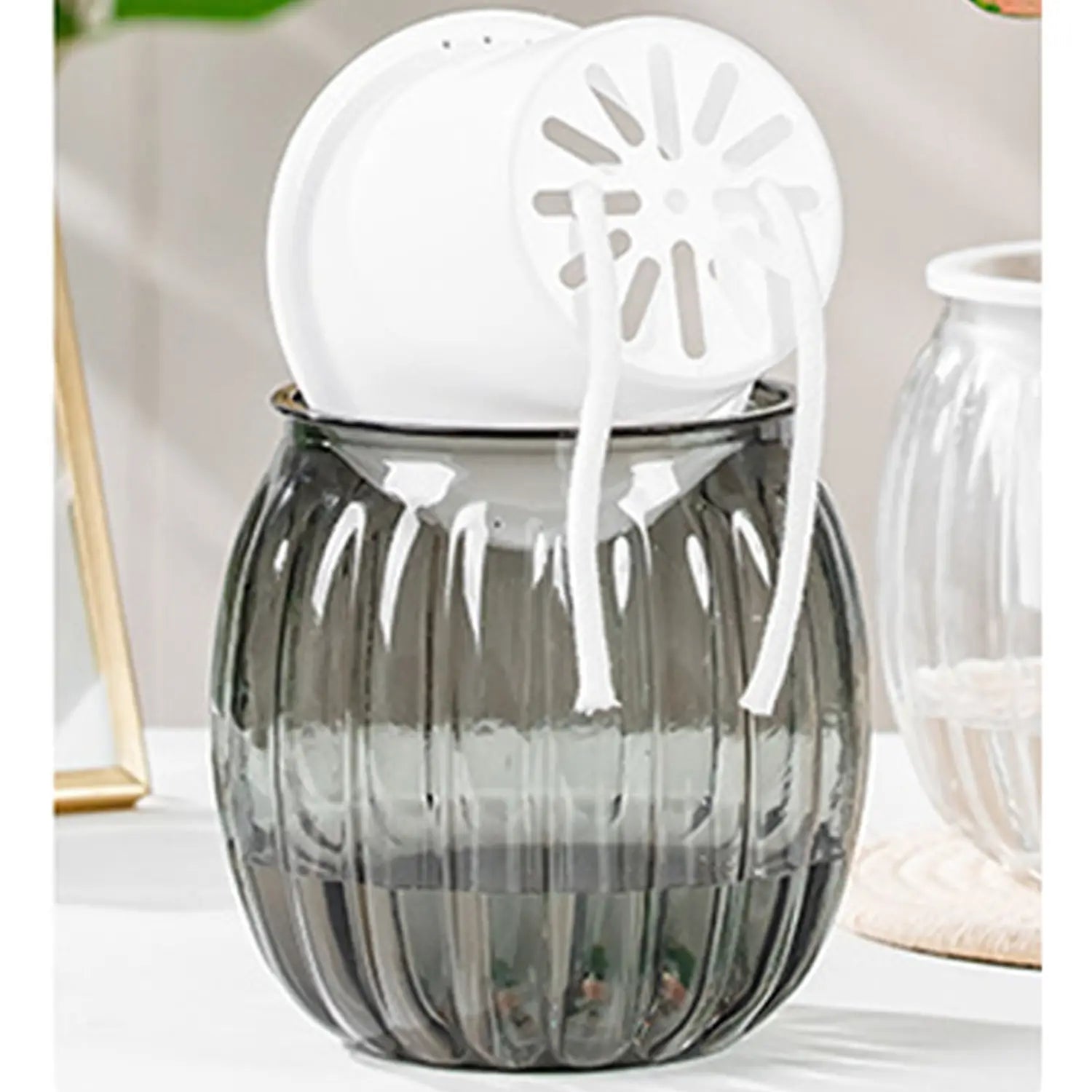 Ein eleganter dunkelgrauer gerippter Glas-Selbstbewässerungs-Pflanzschalen-Topfeinsatz mit strukturierter Oberfläche hält zwei weiße Kunststoff-Siebe.