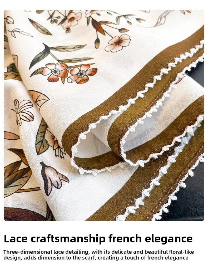 A cream-colored silk floral square scarf with delicate peach and olive floral patterns and a wide brown border featuring intricate white lace detailing along the edge.