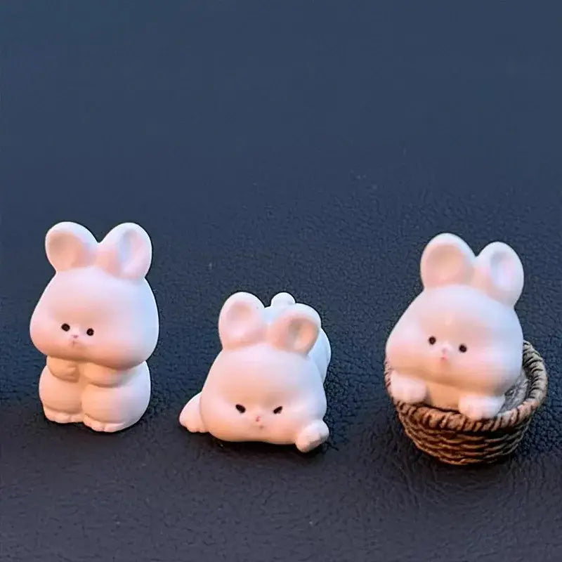 Trois adorables figurines de lapin en céramique blanche avec des traits doux et arrondis et de petits yeux noirs, comme des ornements de tableau de bord de voiture en forme de lapin mignon.