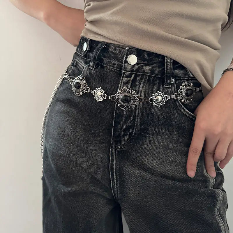 Ceinture de hanche en chaîne pour cosplay ornée, argentée, avec des pierres ovales noires et une ferronnerie complexe, portée par-dessus un jean sombre, pour un accessoire de ceinture de hanche de style gothique punk