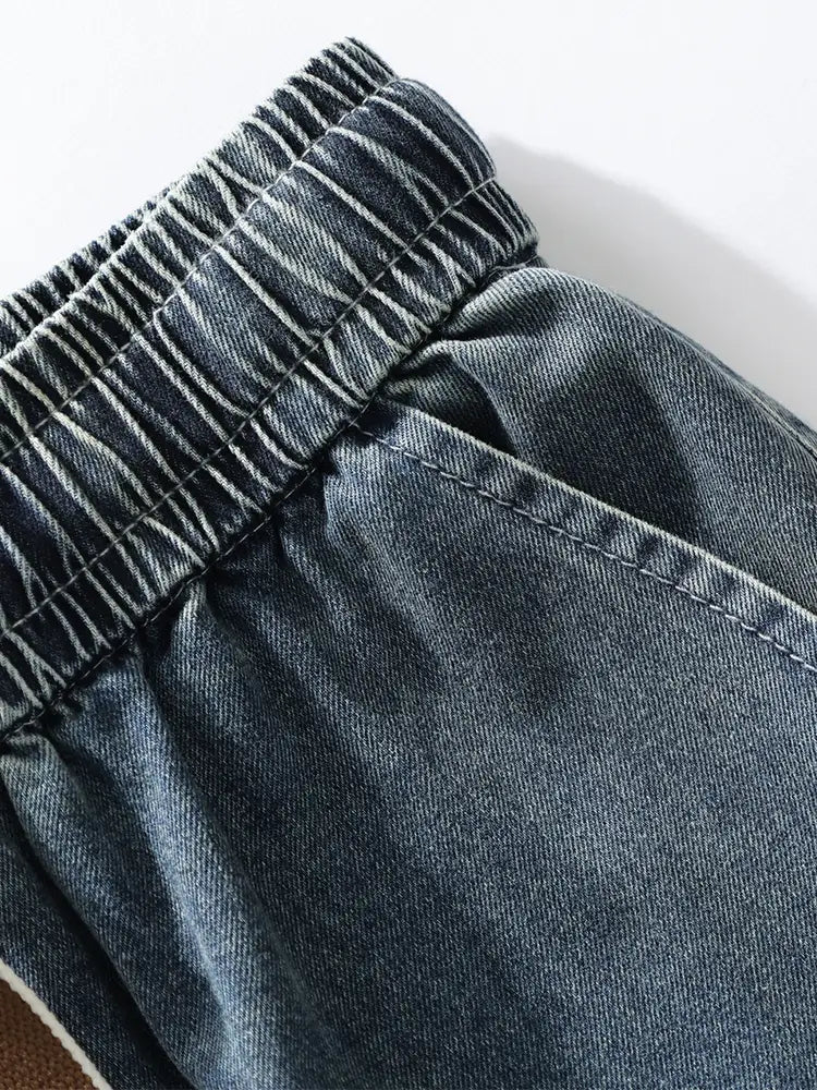 Le pantalon cargo en denim ample pour homme présente des shorts en denim teinte foncée, une taille élastique et des coutures visibles.
