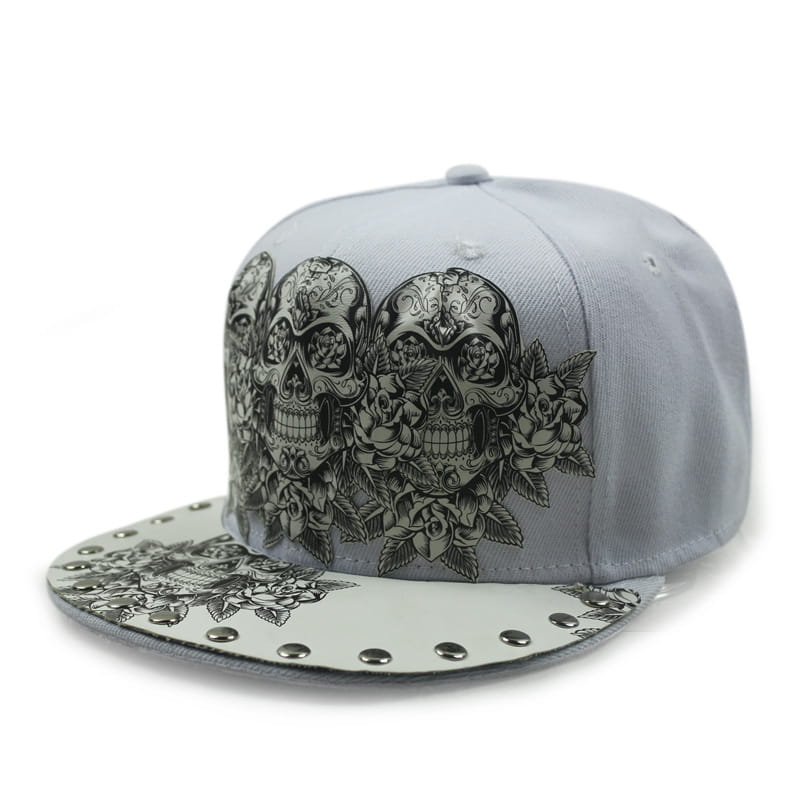 Gray snapback baseball cap featuring intricate black and white sugar skull and floral designs with silver rivet studs along the brim in the Sugar Skull Rivet Snapback Baseball Cap collection.