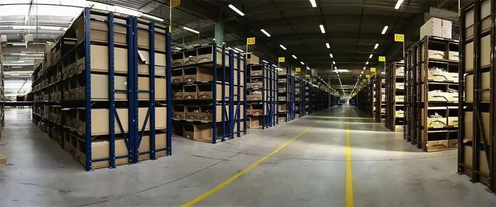 Blau lackierte Metall-Regalsysteme im Lager mit auf mehreren Ebenen gestapelten Kartons, die Verpackungen für ein Induktionsherd-Spielzeug für Kinder mit Sound- und Lichtfunktionen lagern