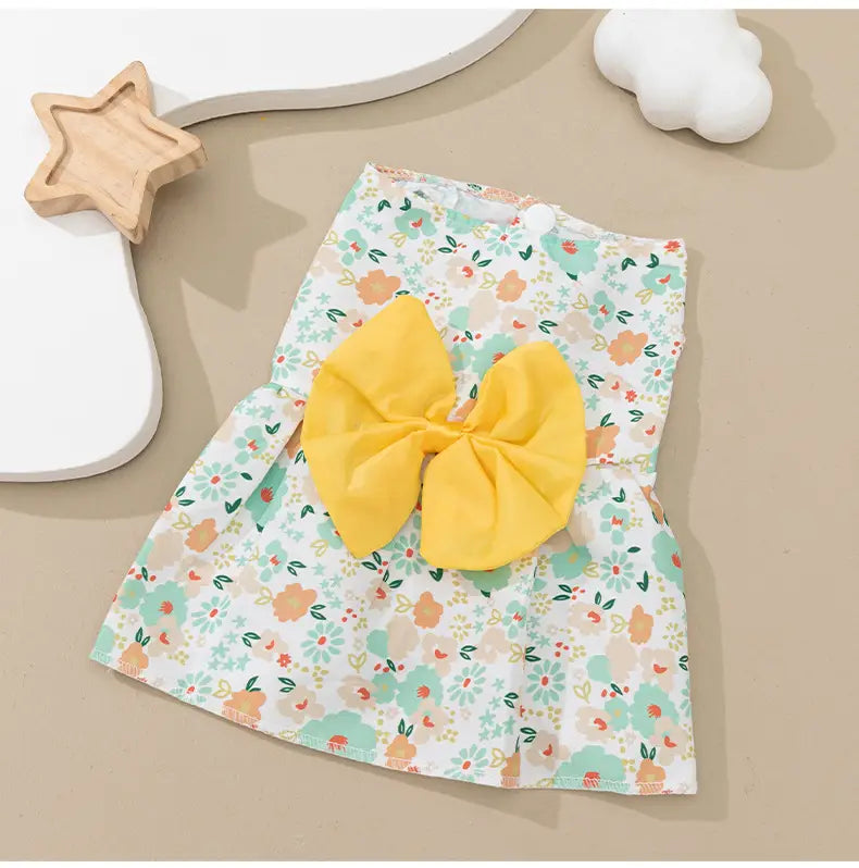 A charming pastel floral dog princess dress featuring a vibrant yellow bow at the center.