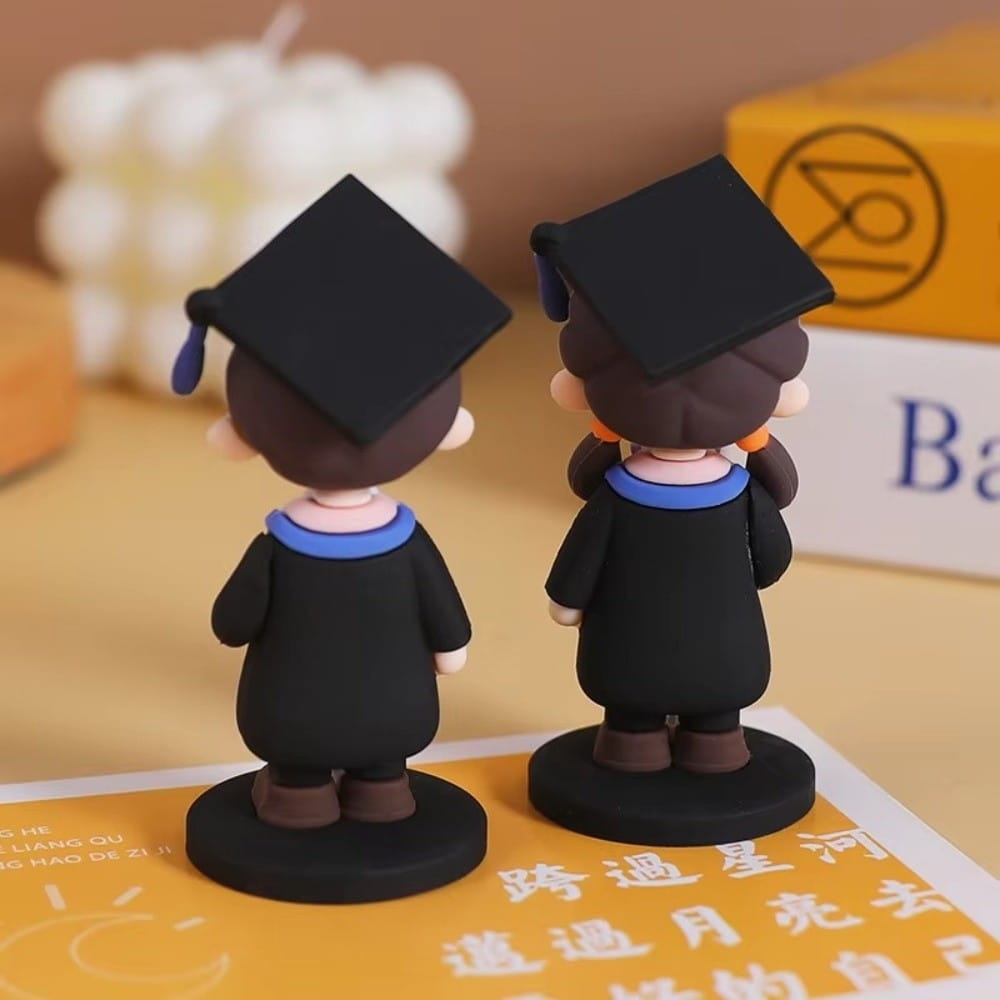 Deux figurines noires à thème de remise des diplômes, avec bordures bleues et glands violets, se tenant sur des bases circulaires, comme sujet de gâteau de remise des diplômes, figurine de diplômé mignonne