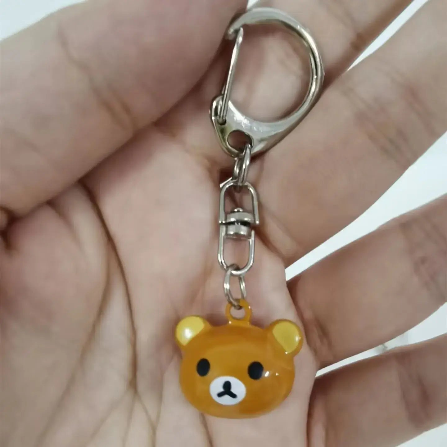 A shiny orange rilakkuma bear keychain with black eyes white nose and mouth and yellow ears from the rilakkuma bear keychain set cute enamel charms.