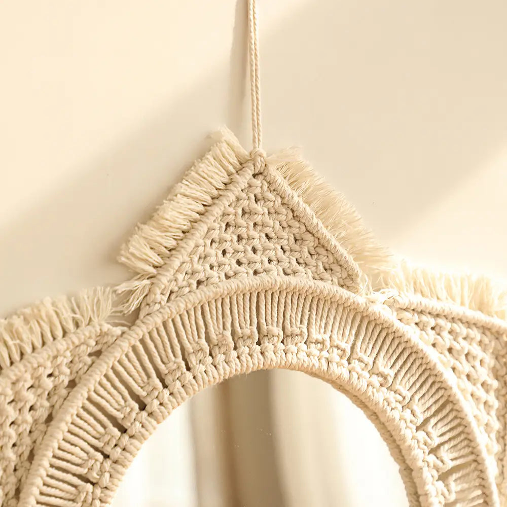 Cream-colored macrame wall mirror with a circular frame and fringed edges suitable for living room home decor.