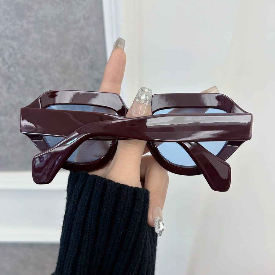 Gafas de sol geométricas burdeos para mujeres y hombres con monturas de acetato brillantes y lentes azules espejadas con un diseño angular moderno.