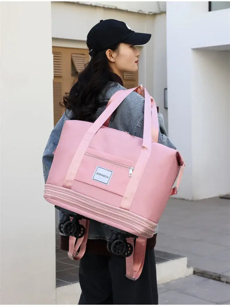 Un sac duffel roulant rose à grande capacité, avec des sangles d’épaule réglables et une poche avant à fermeture éclair pour un usage en voyage.