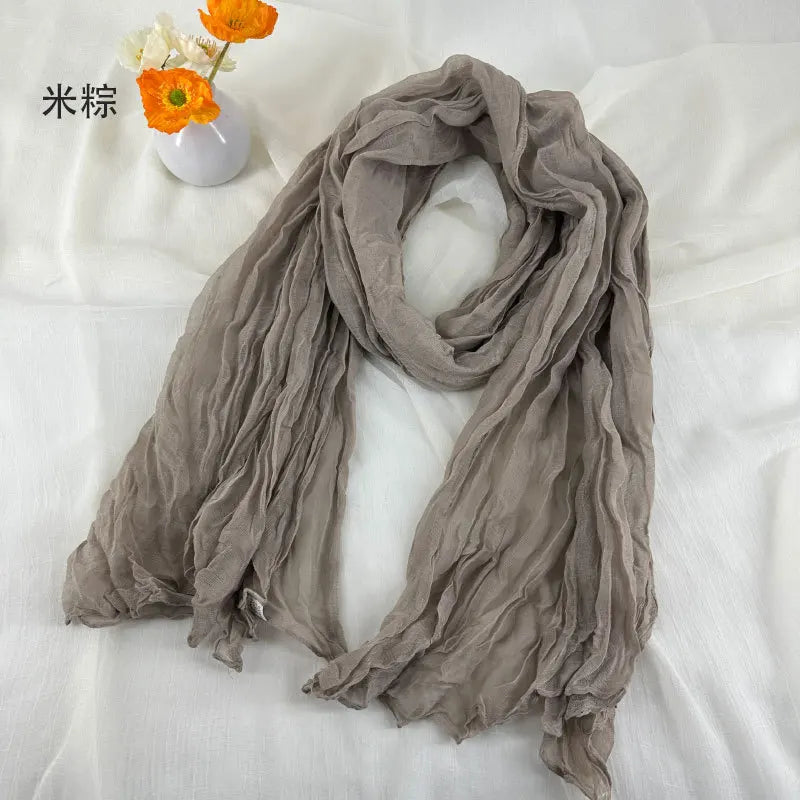 Écharpe en coton et lin plissé gris doux, avec une texture légère, souple et fluide.
