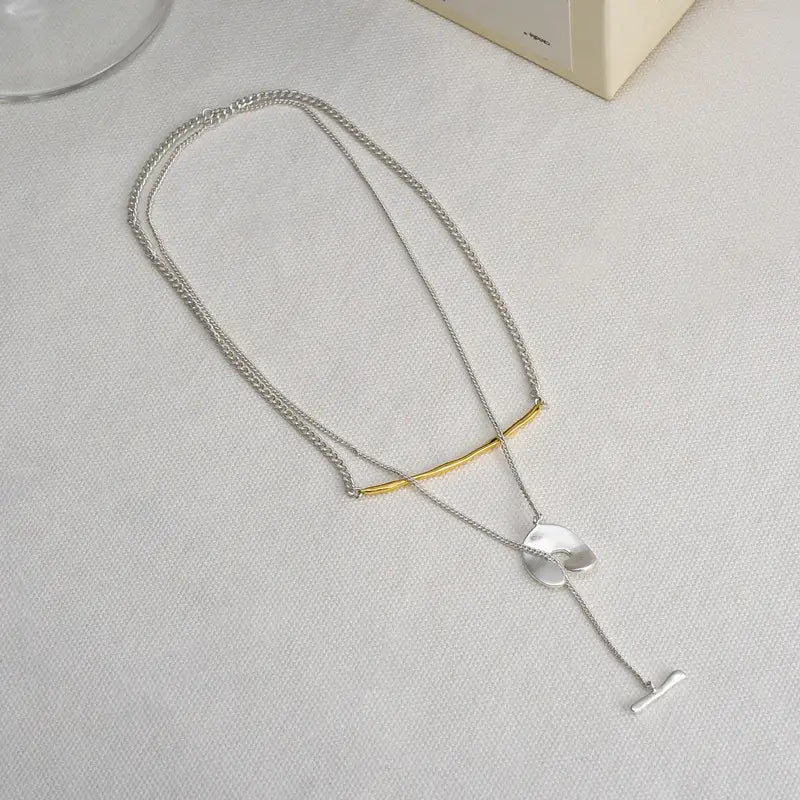 Collier pendentif à superposition de couleurs argent et or pour femmes, présentant une chaîne texturée, un pendentif circulaire plat et une attache à t-bar.