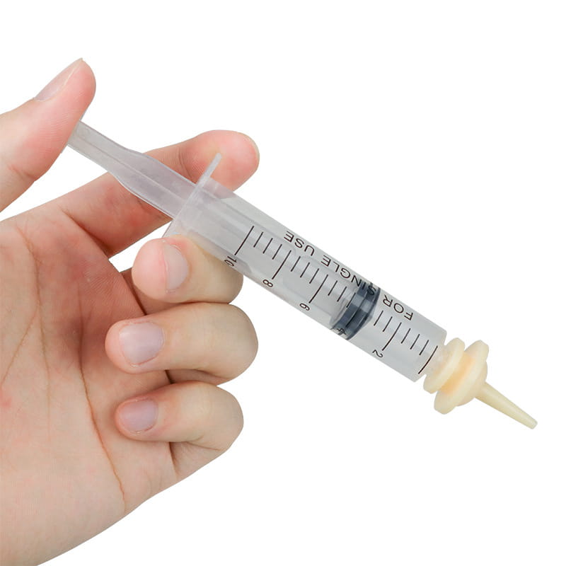 Pet oral syringe made of clear plastic with a beige rubber tip and black measurement markings designed for precise feeding using a silicone nipple feeder.
