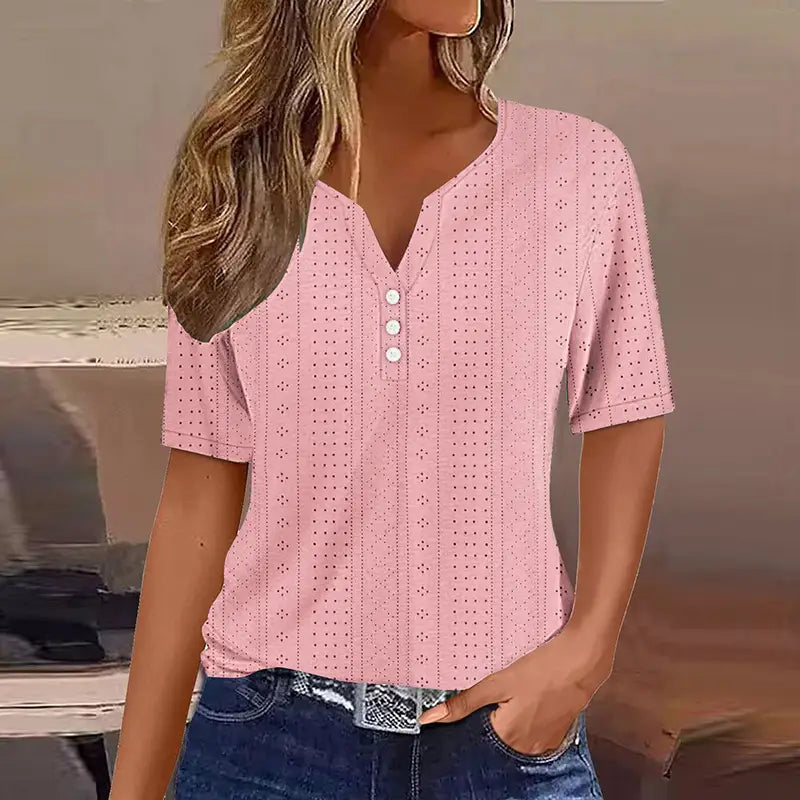 T-shirt boutonné pour femmes à encolure en V et manches courtes, de couleur rose clair, avec un motif ponctué discret et trois boutons blancs alignés sur le devant.