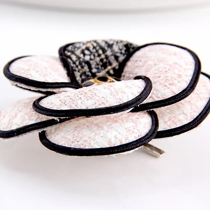 Brosche aus Kamelienstoff in Form einer Blume, gefertigt aus zartem weißem und schwarzem floralen Haarclip aus strukturiertem Tweed, mit kontrastierender schwarzer Einfassung.
