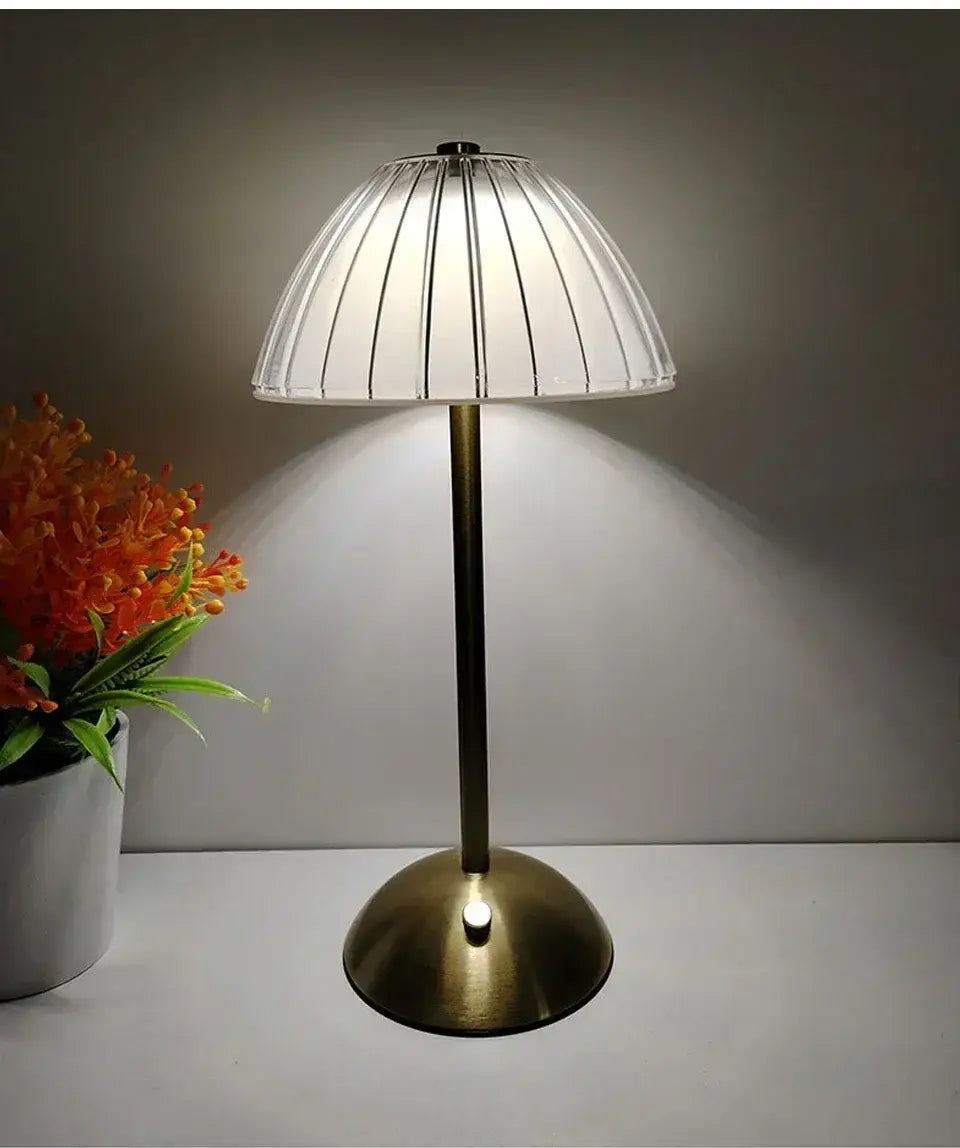 Wiederaufladbare Tischlampe mit Messing-Finish und transluzentem plissierten Glasschirm, die als Lichtquelle dient.