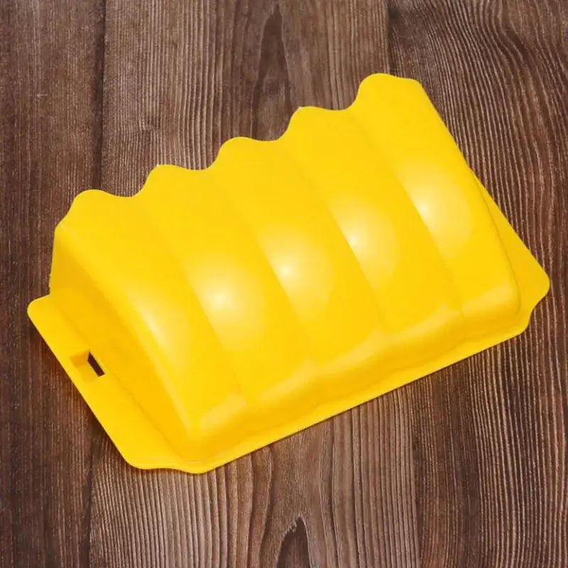 Bright yellow plastic car wheel chock with a wavy ridged surface and a small slot on one end shown as part of an external rabbit hay feeder plastic food rack.