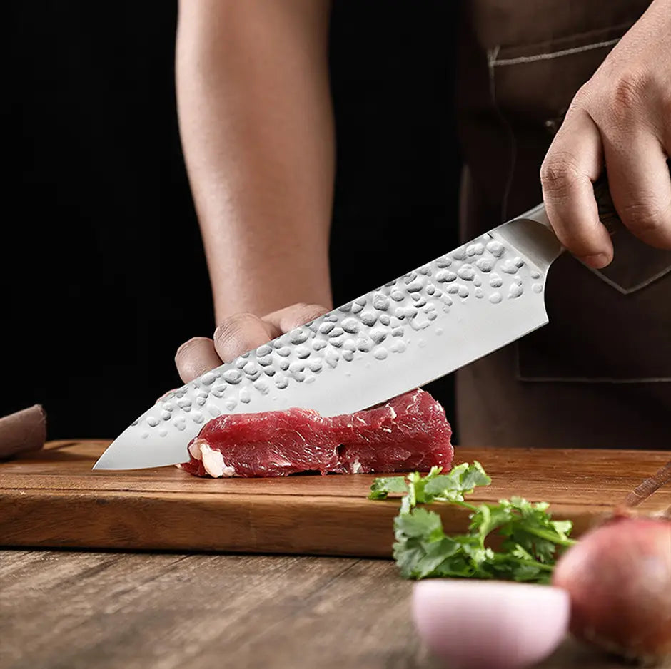 A sleek hammered stainless steel chef knife with a sharp reflective blade and a sturdy handle from the forged stainless steel chef knife set.