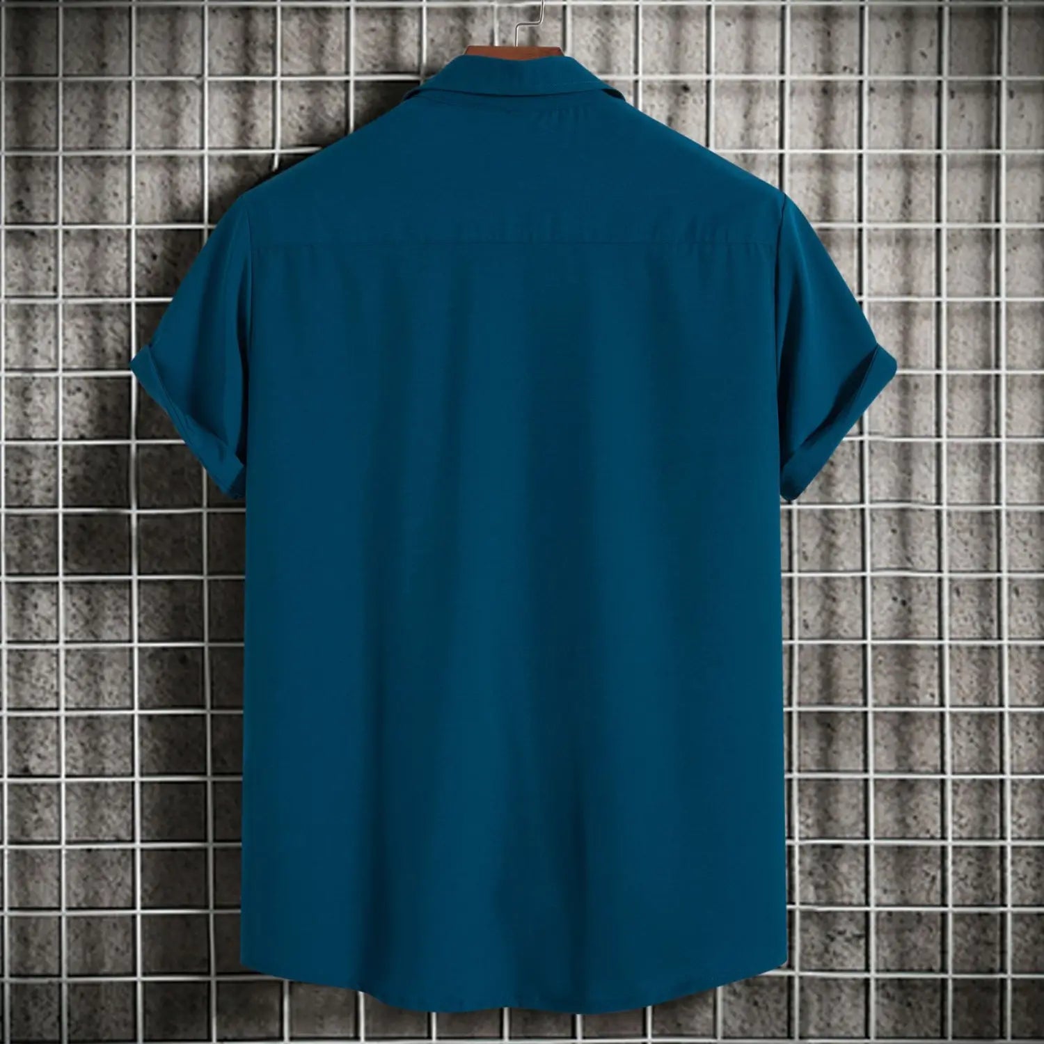 chemise à manches courtes vert turquoise unie pour homme, style mode, unie, avec col classique et design boutonné, affichée sur un cintre en bois contre un arrière-plan à motif quadrillé, convenant comme chemises de plage