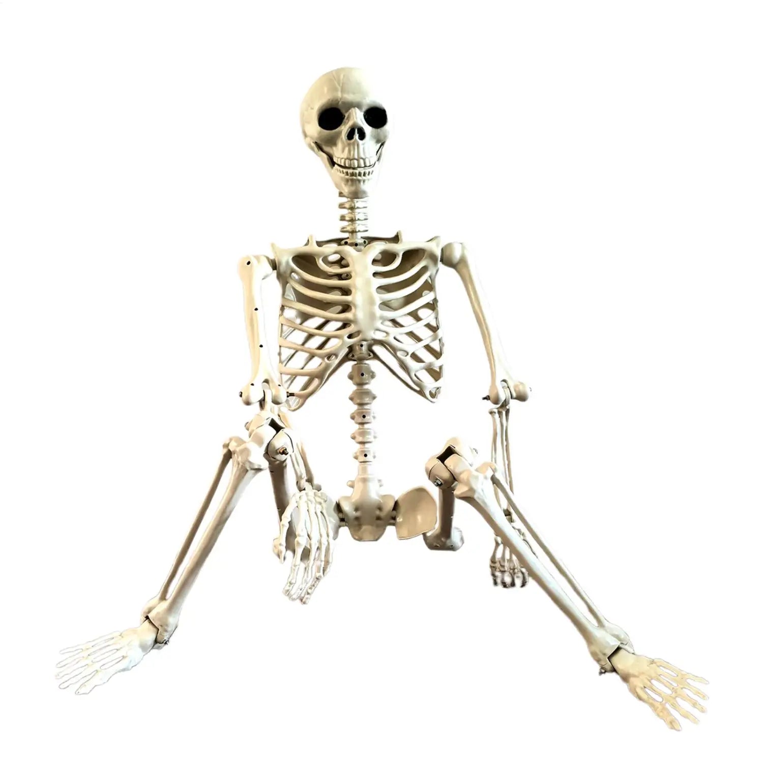 A beige plastic halloween skeleton with articulated joints and black eye sockets posed in a seated position for garden decor or haunted house use.