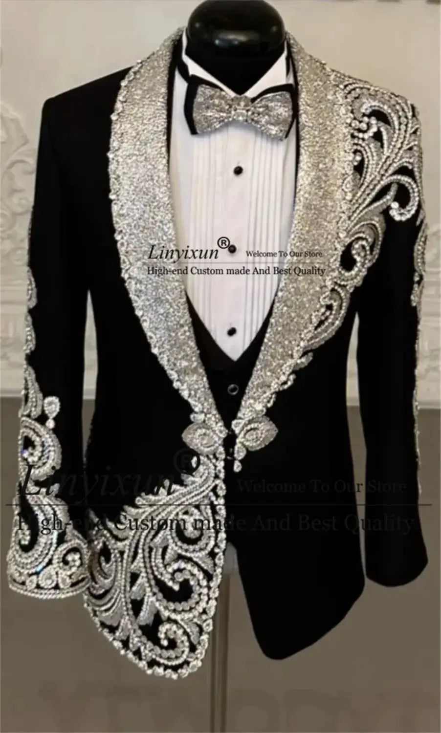 Costume de tuxedo de mariage pour hommes en velours noir, avec une veste de tuxedo noire ornée d’une broderie argentée complexe de perles le long des revers, des épaules et des poignets.