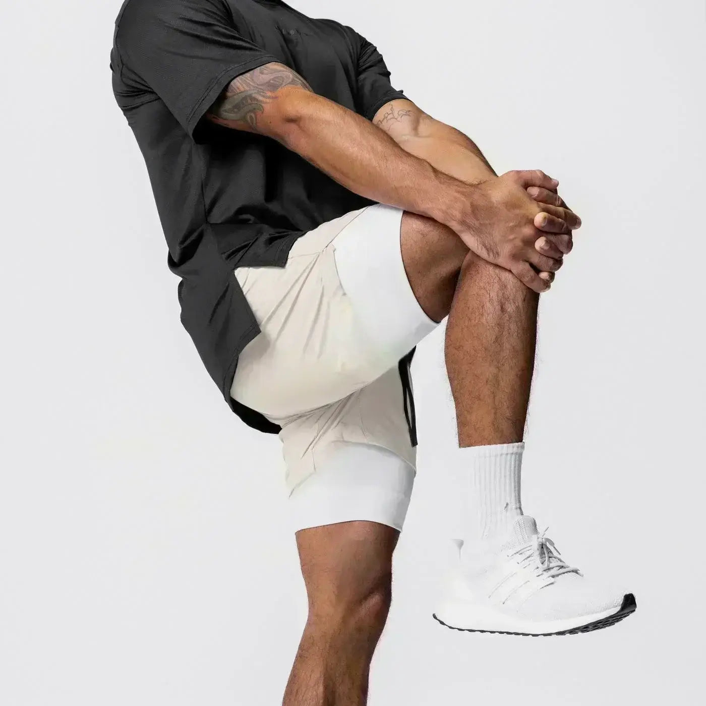 Un par de pantalones cortos de entrenamiento para anime 2 en 1 de color crema para gimnasio con cintura elástica y trabilla para la toalla, con un diseño moderno y elegante y sutiles franjas laterales negras.